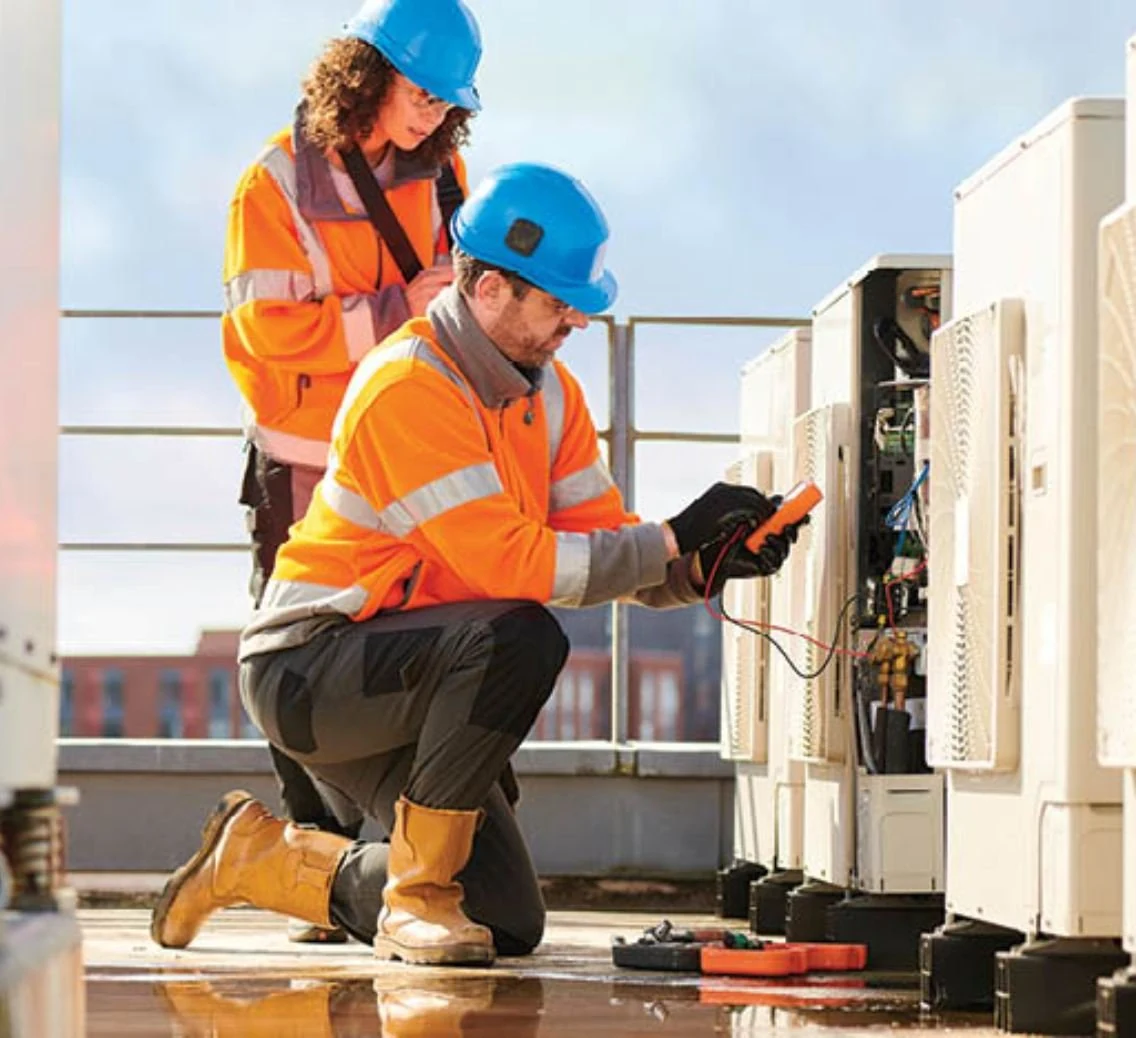 Two engineers testing rooftop air-conditioning condenser units.