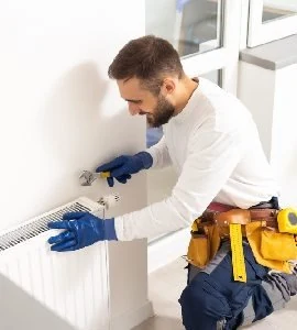 A maintenance technician servicing a wall-mounted heating unit.
